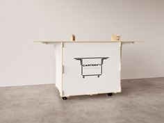 a cart sitting on top of a cement floor next to a white wall with a wooden shelf