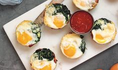 eggs and spinach on mini muffins with ketchup are sitting on a white plate