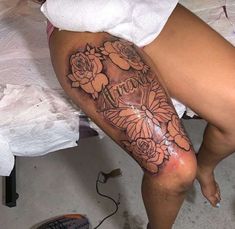 a woman's leg with flowers on it and the word tattoo written in cursive writing