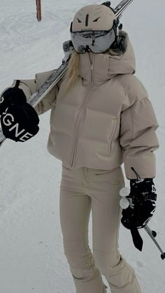 a woman holding skis and poles in the snow