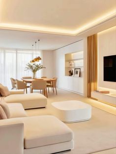 a living room filled with white furniture and a flat screen tv mounted on the wall