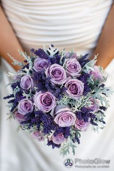 a bride holding a bouquet of purple flowers