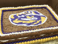 a decorated cake in the shape of a tiger head with purple, yellow and white frosting