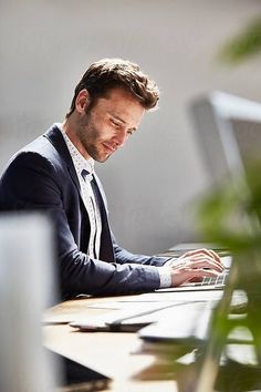 a man sitting at a desk using a laptop computer by luma studio for stockstation