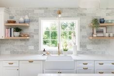 a kitchen with white cabinets and marble backsplash, open shelves above the sink