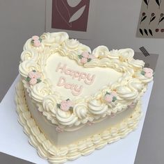 a heart shaped cake sitting on top of a white table next to a card board