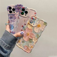 two cases with flowers on them are being held by someone's hand in front of the camera