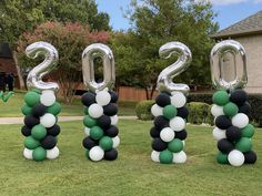 balloons are arranged in the shape of numbers on top of grass, and one balloon is attached to the number two