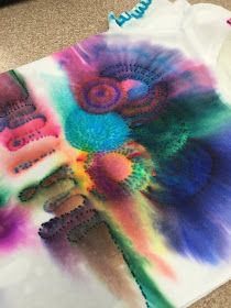 a t - shirt that has been dyed with colorful dyes and is sitting on the floor