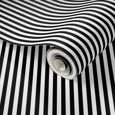 a black and white striped wallpaper with a rolled up roll on the floor next to it