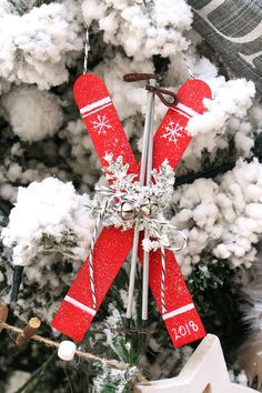 an ornament hanging from a christmas tree decorated with red skis and snowflakes