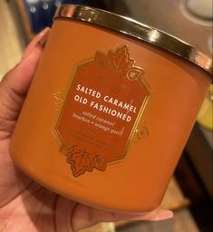 a hand holding a jar of old fashioned salted caramel candle in it's left hand