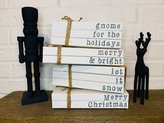 a stack of books sitting on top of a wooden table next to a black figurine