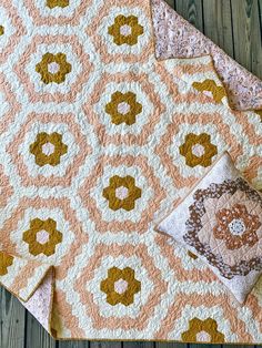 an orange and white quilt sitting on top of a wooden floor next to a pillow