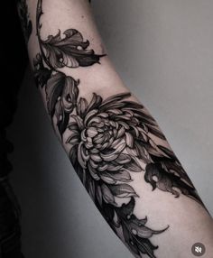 a woman's arm with flowers and leaves on it