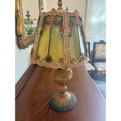 a lamp sitting on top of a wooden table in front of a mirror and chair