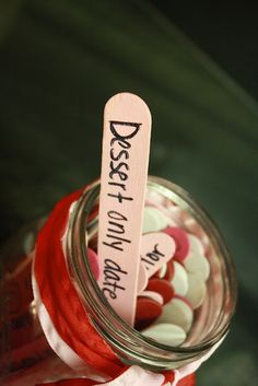 a jar filled with lots of red and white buttons next to a wooden stick that says best mom on it