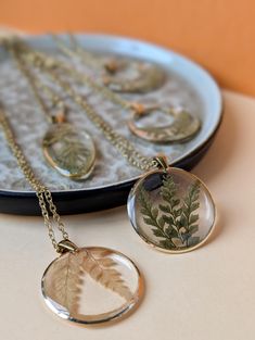 two necklaces with leaves are sitting on a plate