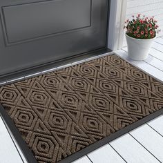 a brown door mat sitting on top of a wooden floor next to a potted plant