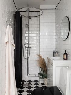 A checkerboard floor paired with a black curtain and subtle black accents in a solid white bathroom