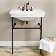 a white sink sitting on top of a wooden floor next to a wall mounted faucet