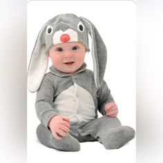 a baby wearing a bunny costume sitting on the ground