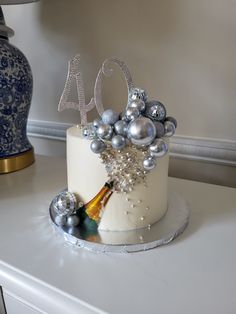 a white cake with silver decorations and a bottle of champagne on the table next to it