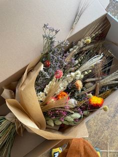 an open cardboard box with dried flowers in it