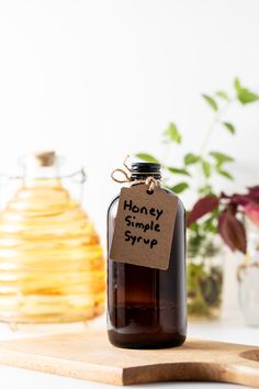 a bottle of honey sits on a cutting board next to a jar of honey syrup