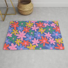 a colorful flower rug on the floor next to a basket