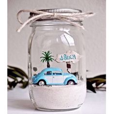 a glass jar filled with sand and a blue car