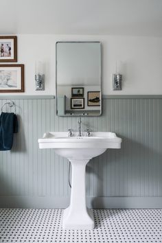 a white pedestal sink sitting under a mirror next to a wall mounted faucet