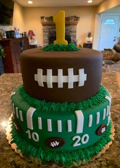 two tiered cake decorated with green and brown icing, footballs on top