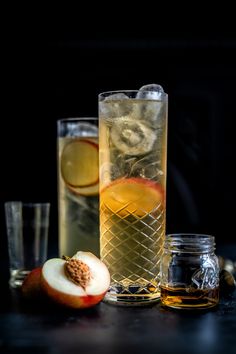 two glasses filled with different types of drinks next to apples and other ingredients on a table