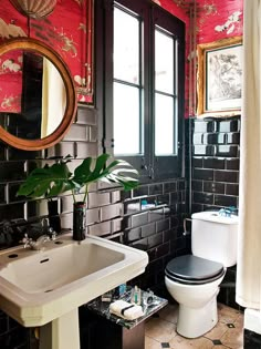 a black and white bathroom with red wallpaper on the walls, a toilet and sink