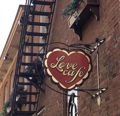 a sign on the side of a building that says love cafe with a red heart