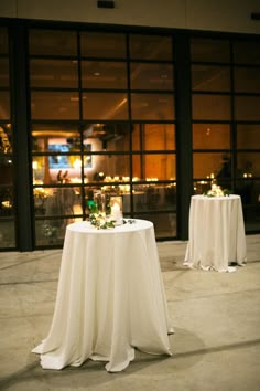 two tables with white linens and candles on them