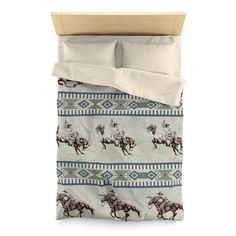 a bed with two pillows and a comforter on top of it, featuring horses