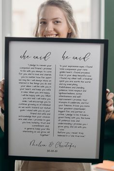 a woman holding up a framed poster with the words she wrote to her husband on it