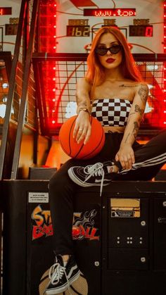 a woman with red hair sitting on top of a box holding a basketball and wearing sunglasses