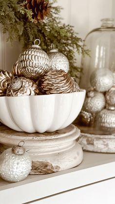 a white bowl filled with christmas ornaments on top of a shelf next to other decorations