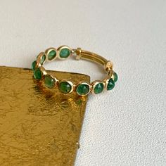 18KT yellow gold ring with round, genuine, bezel-set, emeralds band ring. Great for stacking, wedding band, anniversary, birthstone etc... Totally adjustable to wear on different size fingers! Weight: 1.2 grams Adjustable sizing bar in back, but we can also do up in any size and with other gemstones. (11) Genuine, round, cabochon emeralds measures: 3mm Bezel-set emerald 1.82 carat emeralds Stamped 18K Adjustable Round Emerald Ring As Birthstone, Adjustable Round Emerald Ring With Birthstone, Adjustable Round Emerald Birthstone Ring, Adjustable Stackable Emerald Rings, Everyday Green Stackable Rings With Bezel Setting, Adjustable Gold Stackable Emerald Ring, Adjustable Yellow Gold Emerald Ring, Adjustable Emerald Ring With Bezel Setting, Adjustable Stackable Gold Emerald Ring