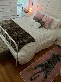 a white bed sitting in a bedroom next to a dresser and rug on top of a hard wood floor