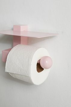 a toilet paper holder is mounted on the wall with a pink shelf and shelving