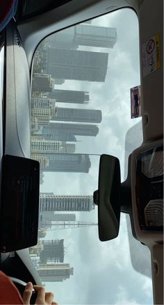 a view from the inside of a bus looking down at buildings and clouds in the sky