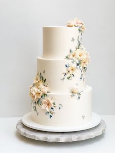 a three tiered wedding cake with flowers painted on it