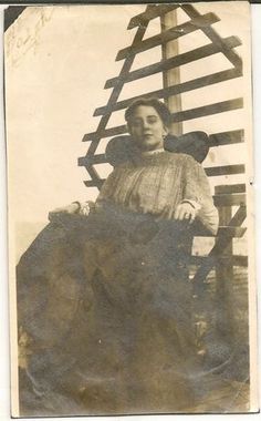 an old black and white photo of a woman sitting on a chair