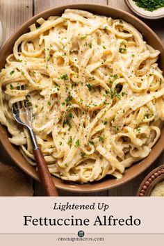 an overhead view of a bowl of fettuccine alfredo on a wooden table