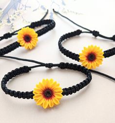 Add a touch of boho elegance to your look with our Sunflower Black Cord Bracelet. This unique piece of jewelry showcases a stunning sunflower charm intricately designed on a black cord, making it a perfect accessory for bohemian-inspired weddings and special occasions. The adjustable cord ensures a comfortable fit for all wrist sizes. Our sunflower bracelet also makes a thoughtful bridesmaid gift, symbolizing beauty, happiness, and growth. Each bracelet is custom-made with attention to detail and crafted with love. Embrace the free-spirited charm of sunflowers and make a statement with this captivating piece. Product Details: Sunflower bracelet with a black cord Materials: Handmade Sunflower, waxed cord Length: Adjustable for a comfortable fit Charm Size: Approx. 1 inch (2.5 cm) Perfect fo Sunflower Jewelry Diy, Sunflower Things, Sunflower Stuff, Jewelry For Bridesmaids, Fall Wedding Jewelry, Sunflower Accessories, Sunflower Bracelet, Sunflower Charm, Sunflower Jewelry