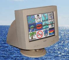 an old computer monitor sitting on top of a wooden stand in front of the ocean